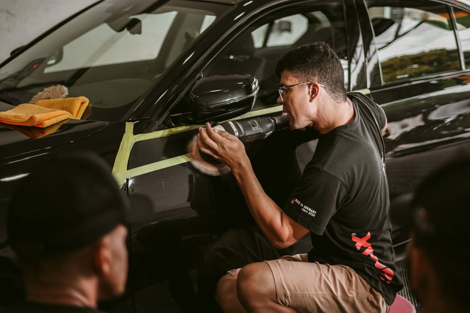 Car detailer working meticulously on vehicle paint